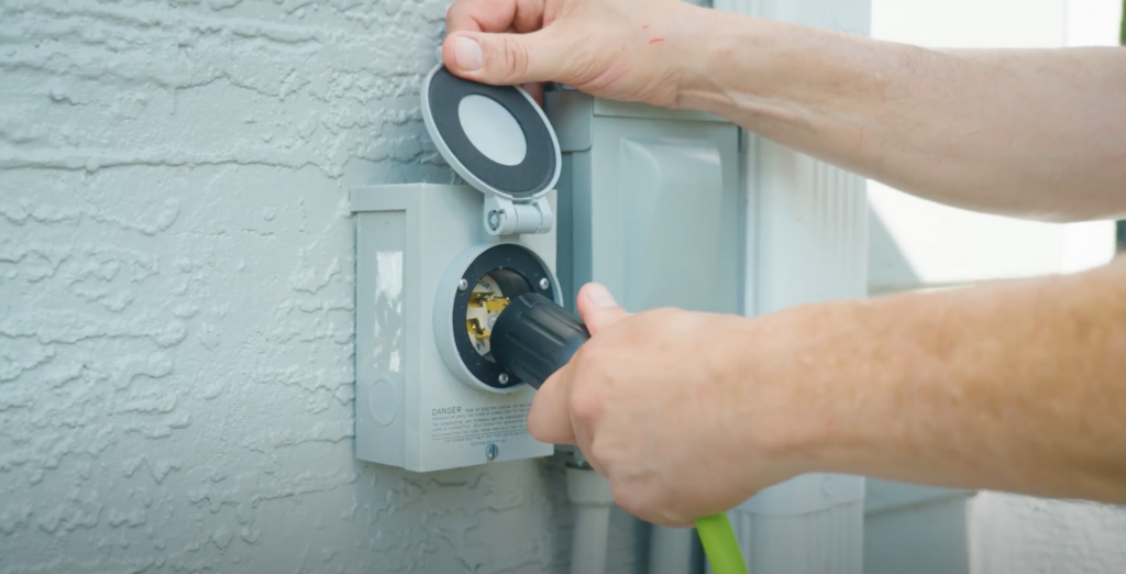 Man plugging generator cord into generator inlet